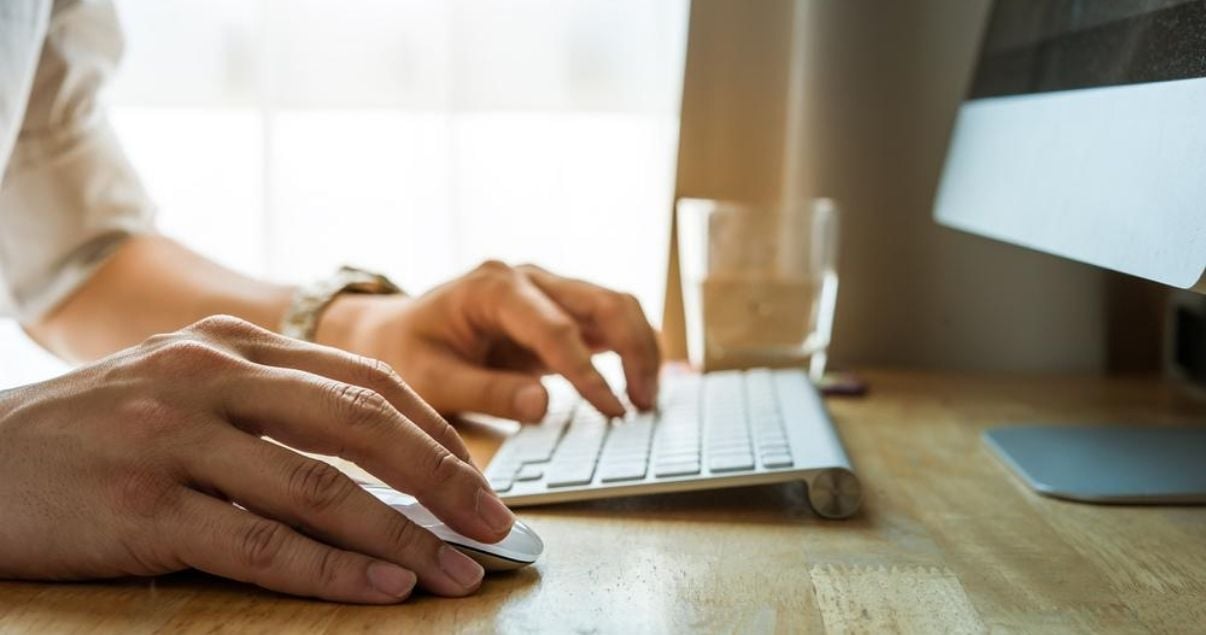 Manos de una persona utilizando un teclado en su casa durante el teletrabajo gracias a la tecnología y la digitalización de empresas